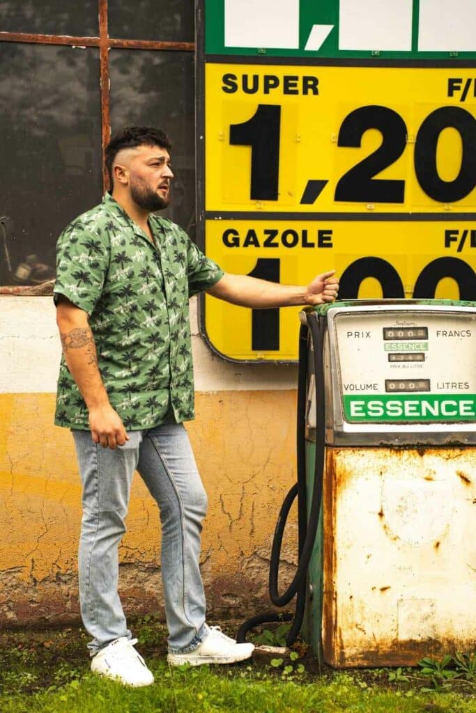 Homme portant une chemise western verte style chasse et outdoor devant une ancienne station-service