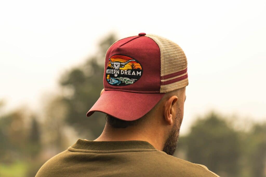 homme portant une casquette trucker western rouge filet vue de dos en extérieur