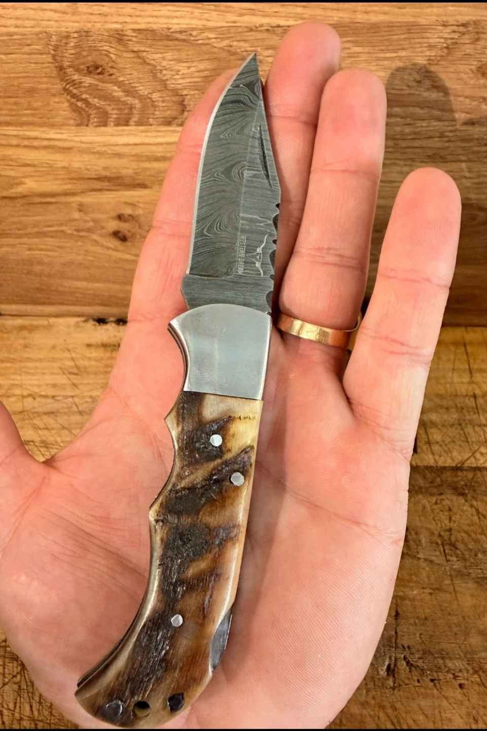 Couteau de chasse artisanal en acier damas avec manche en corne naturelle. Modèle Western Dream gravé sur la lame, idéal pour chasseurs et passionnés d’univers western.