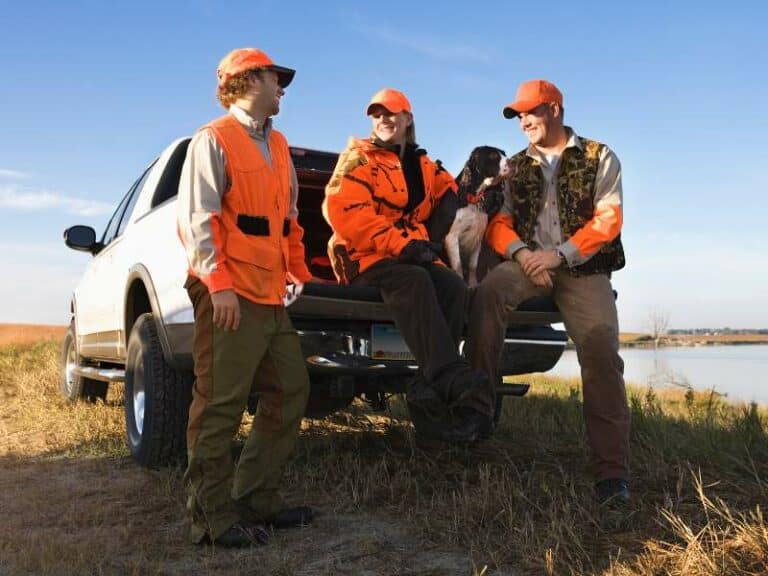 Chasseurs en tenue orange partageant un moment ensemble illustrant la transmission et la passion de la chasse entre générations
